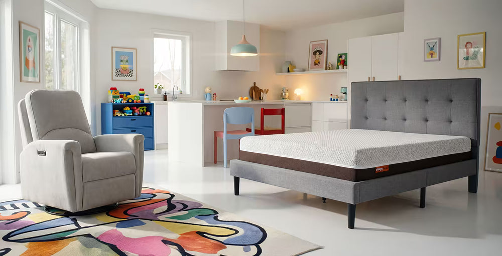 Modern bedroom with a gray upholstered bed, armchair, and colorful rug.